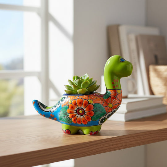 The Talavera Hub handcrafted ceramic Brachiosaurus planter with vibrant floral patterns and a small green succulent.