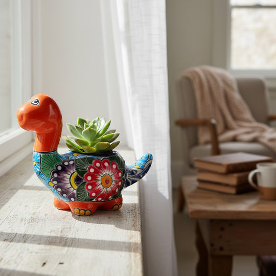 The Talavera Hub handcrafted ceramic Brachiosaurus planter with vibrant floral patterns and a green succulent.