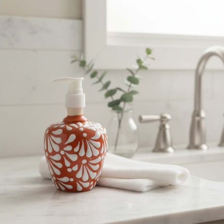 The Talavera Hub handcrafted ceramic soap dispenser with a brown and white floral motif on a marble bathroom counter.