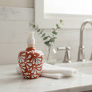 The Talavera Hub handcrafted ceramic soap dispenser with a brown and white floral motif on a marble bathroom counter.