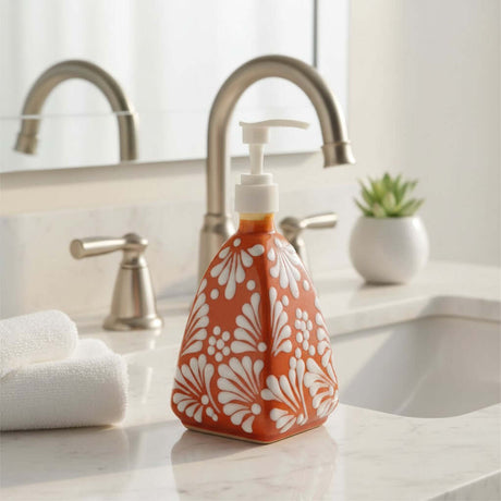 The Talavera Hub handmade ceramic soap dispenser with a brown and white pyramid floral pattern on a bathroom vanity.
