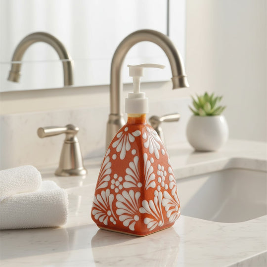 The Talavera Hub handmade ceramic soap dispenser with a brown and white pyramid floral pattern on a bathroom vanity.