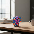The Talavera Hub hand-painted ceramic axolotl figurine with vibrant Mexican folk art patterns on a wooden desk.