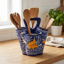 The Talavera Hub handmade ceramic utensil holder in blue and white with hand-painted butterfly motifs on a wooden counter.