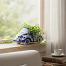 The Talavera Hub blue and white handmade ceramic car planter with trailing green ivy on a sunny windowsill.