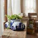 The Talavera Hub handmade blue and white ceramic car planter with a succulent, displayed on a rustic windowsill.