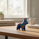 The Talavera Hub hand-painted ceramic donkey figurine with vibrant multicolor Mexican folk art patterns on a desk.