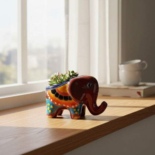 The Talavera Hub hand-painted ceramic elephant planter with colorful floral patterns holding a small succulent.