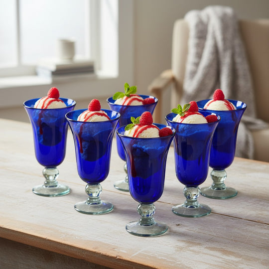 The Talavera Hub hand-blown cobalt blue glass goblets with clear stems, 7" tall, perfect for desserts or drinks.