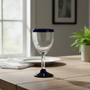 The Talavera Hub hand-blown Mexican wine glass with a clear bowl, cobalt blue rim, and black base. Holds 12 oz.
