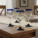 The Talavera Hub hand-blown Mexican wine glasses feature clear glass with a cobalt blue rim and base. Set of 4, 12 oz capacity.