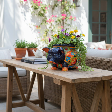 The Talavera Hub hand-painted ceramic pig planter with colorful floral and geometric patterns, blue eyes, and orange hooves.