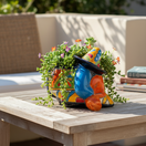 The Talavera Hub colorful ceramic planter shaped like a sleeping man in a sombrero, hand-painted with orange, blue, green, and red.