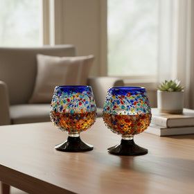 The Talavera Hub confetti rock shot glass with blue rim and pedestal base, made of lead-free glass.