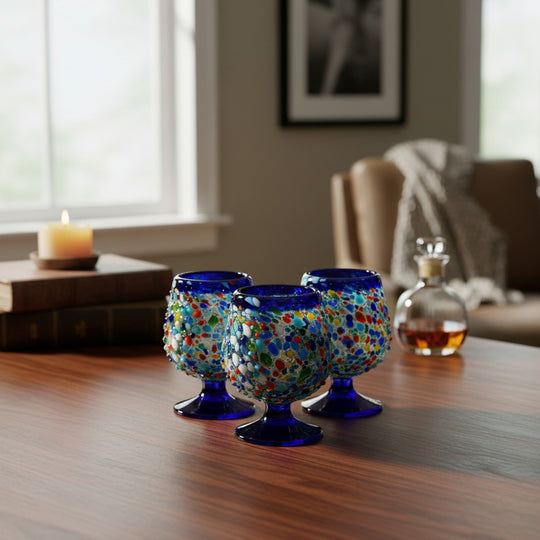 The Talavera Hub confetti rock shot glass with blue rim and pedestal base, handmade from lead-free glass.