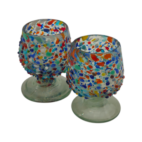 The Talavera Hub handcrafted confetti rock shot glass with colorful glass beads fused into a clear, pedestal base.
