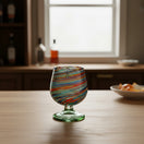 The Talavera Hub hand-blown Mexican shot glass with confetti swirl design in red, blue, green, and amber glass.