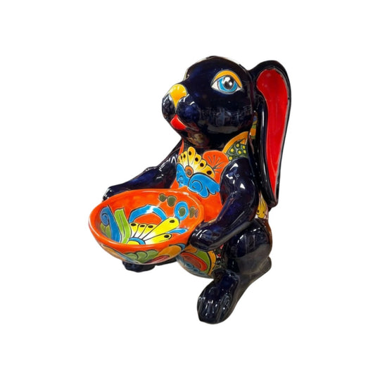 The Talavera Hub dark blue ceramic bunny statue with red ears, holding a colorful Talavera bowl. Handcrafted Mexican folk art.