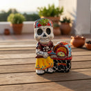 The Talavera Hub 8" Day of the Dead skeleton chef figurine in colorful attire next to a hand-painted Mexican oven.