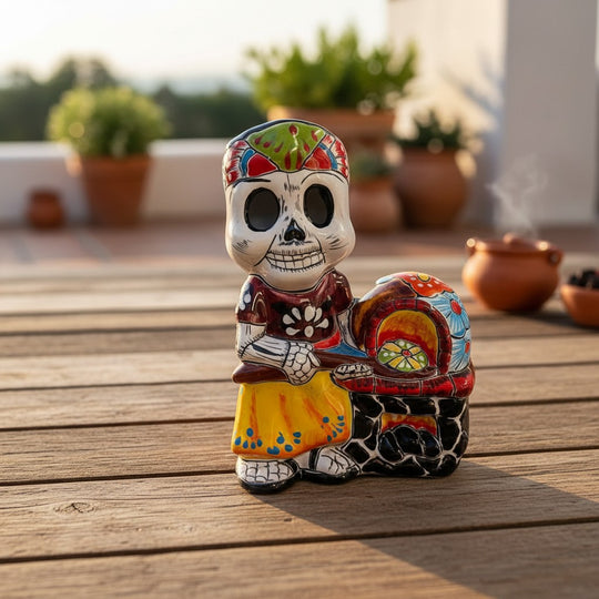 The Talavera Hub 8" Day of the Dead skeleton chef figurine in colorful attire next to a hand-painted Mexican oven.