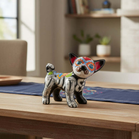 The Talavera Hub hand-painted ceramic Chihuahua statue with Day of the Dead motifs in black, white, orange, blue, and red.