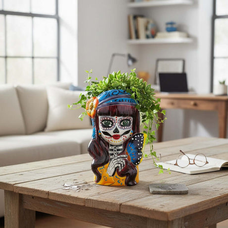 The Talavera Hub Day of the Dead skull planter with butterfly and floral accents, hand-painted ceramic in orange, blue, and purple.
