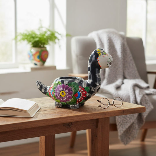 The Talavera Hub black ceramic brachiosaurus planter with colorful floral and skull motifs, 8" tall.