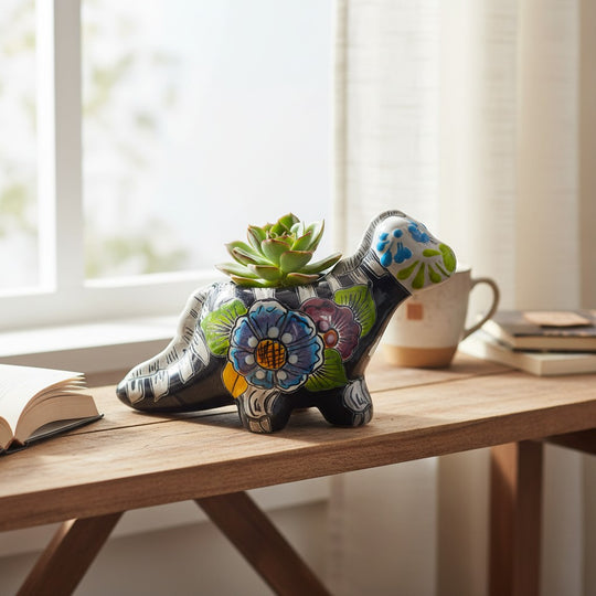 The Talavera Hub black ceramic dinosaur planter with hand-painted floral motifs in orange, blue, green, and red. Day of the Dead style.