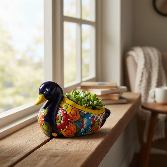 The Talavera Hub handmade Mexican duck planter with colorful floral patterns holding a small green succulent.
