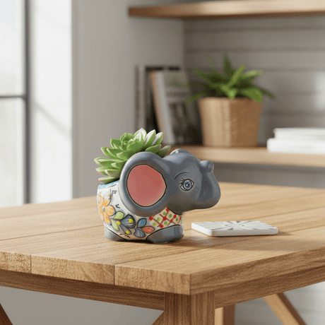 The Talavera Hub hand-painted gray ceramic elephant flower pot with colorful floral designs and blue accents.