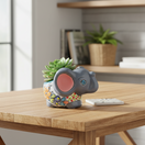 The Talavera Hub hand-painted gray ceramic elephant flower pot with colorful floral designs and blue accents.