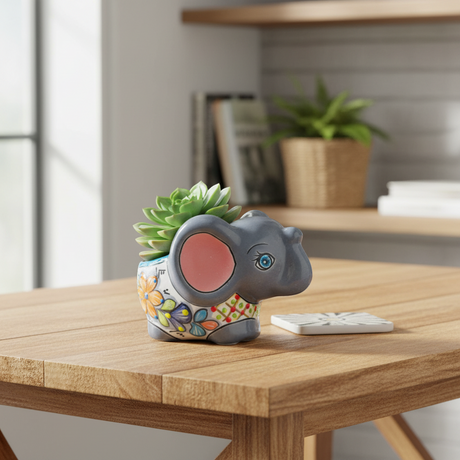The Talavera Hub hand-painted gray ceramic elephant flower pot with colorful floral designs and blue accents.