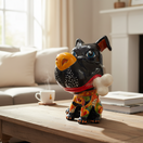 The Talavera Hub extra large black ceramic dog with a yellow nose, holding a bone in its mouth, wearing a red collar and colorful patterned clothing.