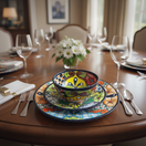 The Talavera Hub 51-piece dinnerware set with vibrant floral patterns in blue, yellow, green, and orange. Hand-painted ceramic.