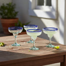 The Talavera Hub Hand-Blown Mexican Margarita Glasses with cobalt blue rims and clear, green-tinted recycled glass bodies. Set of 4.