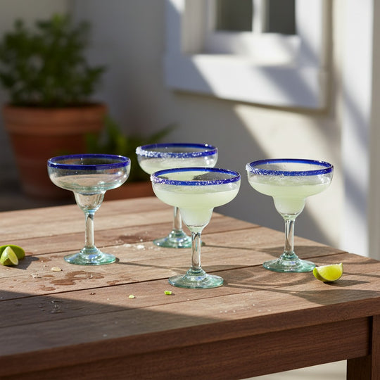 The Talavera Hub Hand-Blown Mexican Margarita Glasses with cobalt blue rims and clear, green-tinted recycled glass bodies. Set of 4.