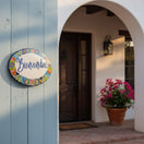 The Talavera Hub hand-painted ceramic Bienvenidos plaque with floral border in blue, orange, green, yellow, and red.