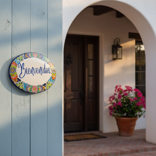 The Talavera Hub hand-painted ceramic Bienvenidos plaque with floral border in blue, orange, green, yellow, and red.