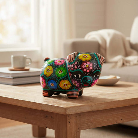 The Talavera Hub handmade ceramic piggy bank featuring vibrant hand-painted floral patterns on a black background.