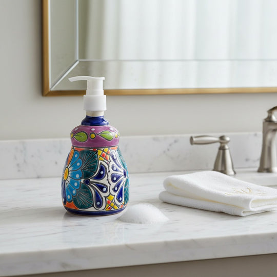 The Talavera Hub handcrafted ceramic soap dispenser with vibrant multicolor floral patterns on a marble bathroom vanity