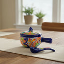 The Talavera Hub hand-painted ceramic soup bowl with lid and matching spoon featuring vibrant Mexican floral patterns.