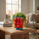 The Talavera Hub hand-painted ceramic face planter in red, orange, blue, and yellow with black eyes and detailed headdress.