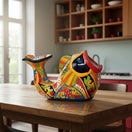 The Talavera Hub hand-painted ceramic fish planter in vibrant orange, green, yellow, red, and blue with floral motifs.