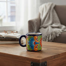 The Talavera Hub hand-painted ceramic coffee mug with vibrant floral patterns in blue, red, and green on a wood table.