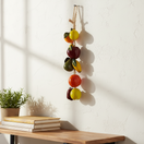 The Talavera Hub hand-painted ceramic fruit garland featuring apples, oranges, and pears in vibrant colors, strung on twine.