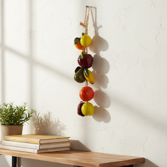 The Talavera Hub hand-painted ceramic fruit garland featuring apples, oranges, and pears in vibrant colors, strung on twine.