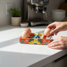 The Talavera Hub hand-painted ceramic egg holder with floral and butterfly motifs in red, yellow, blue, and green.