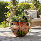 The Talavera Hub hand-painted terracotta planter with desert motifs of cacti and sunbursts on a wooden patio deck.