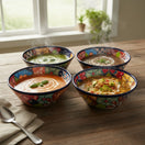 Four The Talavera Hub handmade ceramic soup bowls with vibrant hand-painted Mexican patterns on a rustic wooden table.