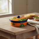 The Talavera Hub handmade orange ceramic tortilla warmer with colorful cactus and floral Talavera patterns and a blue knob.